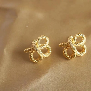 Vue macro de boucles d'oreilles double nœud plaquées or avec texture de corde torsadée