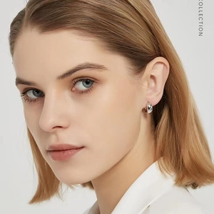 Gros plan d'une boucle d'oreille créole en argent poli portée par un mannequin