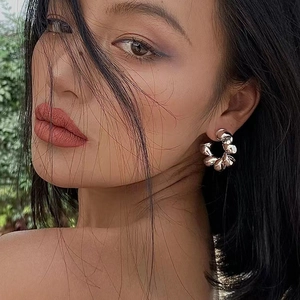 Silver chunky twisted rope hoop earrings with mirror finish worn by a fashion model outdoors