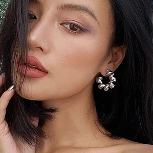 Silver metallic C-shaped earrings with crinkled texture shown on female model