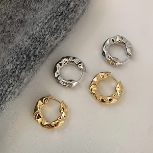 Irregular textured hoop earrings in gold and silver metal finish with a lava-like surface