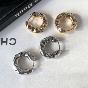 Detail shot of chunky gold and silver earrings with irregular lava texture finish