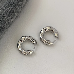 Detail of silver hoop earrings with irregular crinkle texture and liquid metal finish