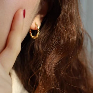 Macro shot of gold textured hoop earrings with detailed beadwork texture on model