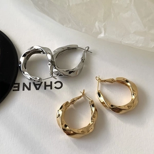 Macro shot of irregular twisted geometric hoop earrings in gold and silver finish