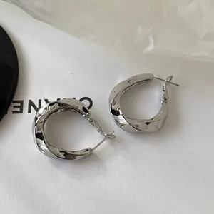 Detailed view of silver twisted geometric oval hoop earrings with polished metal finish