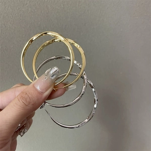 Polished chunky gold and silver twisted hoop earrings held by a model for a stylish look