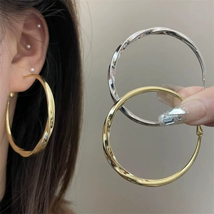 Chic twisted metal hoop earrings in gold and silver finish for a bold minimalist look