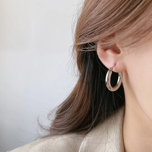 Primo piano di orecchini a cerchio in argento lucido su una modella dallo stile minimal