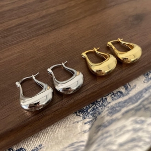Polished gold and silver U-shaped hoop earrings displayed on a dark wooden background
