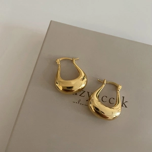 Detailed macro view of 18K gold-plated U-shaped earrings on a premium gift box
