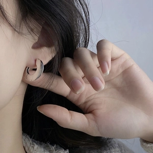 Polished silver C-shaped hoop earrings for women showing a minimalist metal texture on ear