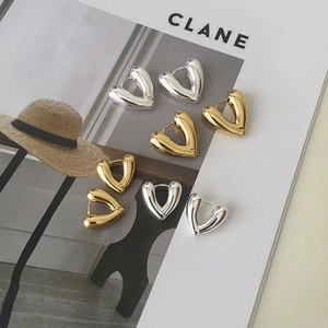 Polished gold and silver V-shaped heart earrings displayed on a fashion magazine