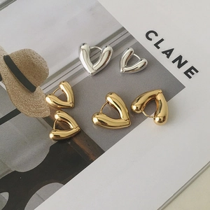 Detailed view of 18K gold and silver heart-shaped hoop earrings on a magazine background