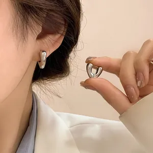 Close-up of polished silver heart hoop earrings worn to show size and mirror finish