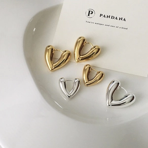 Polished 18K gold and silver chunky heart hoop earrings shown on a white ceramic tray