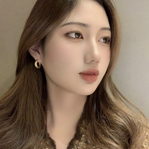 Close-up of golden hoop earrings with textured finish worn by a model in natural light