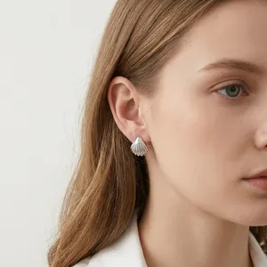Minimalist silver shell stud earrings with textured finish shown on female model
