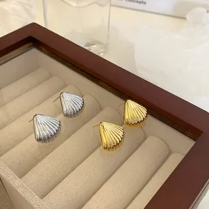 Macro detail of gold and silver shell earrings with textured stripes in a velvet box