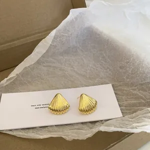 Detail of shell-shaped gold earrings placed in a premium minimalist gift box packaging