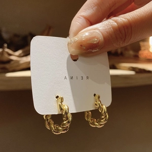 Détail de boucles d'oreilles créoles plaquées or 18K avec un design torsadé texturé