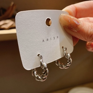Gros plan de boucles d'oreilles créoles torsadées argentées sur carte de support