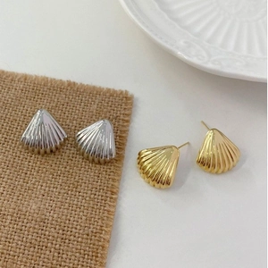 Minimalist shell-shaped metal stud earrings in gold and silver plating with ribbed texture
