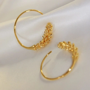 Elegant gold wheat ear hoop earrings displayed on white silk background