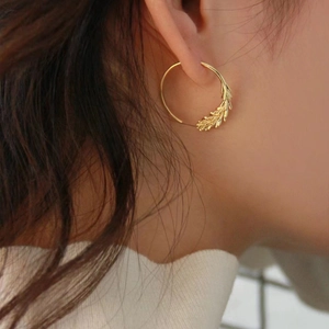 Golden hoop earrings with wheat ear design shown on a model with brown hair