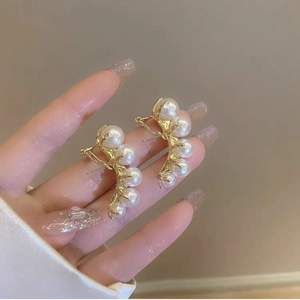 Macro detail of multi-pearl gold cluster earrings with an elegant branch design