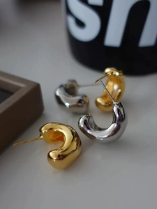 Macro shot of minimalist thick C-shaped hoop earrings in polished gold and silver finishes