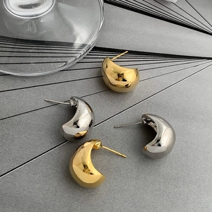 Macro di orecchini a goccia lucidi oro e argento su uno sfondo moderno strutturato