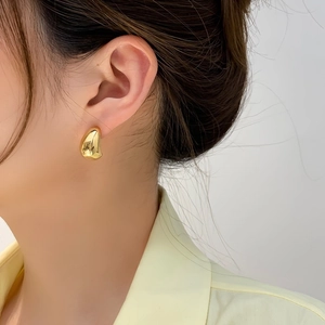 Dettaglio dell'orecchino a goccia d'oro minimalista con finitura a specchio lucidata
