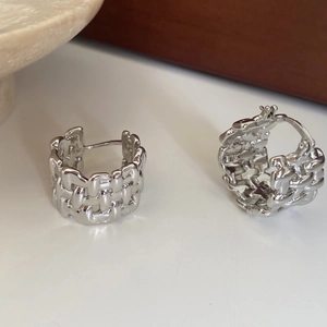 Detailed close-up of silver C-shaped chunky earrings with woven texture and polished finish