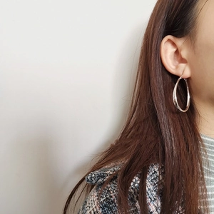 Close-up of polished silver hoop earrings in a teardrop shape worn by a model