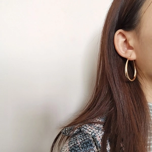 Close-up of polished 18K gold-plated large hoop earrings on model with glossy finish