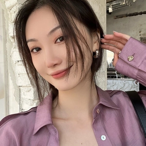 Polished silver irregular C-shaped hoop earrings worn with purple silk shirt