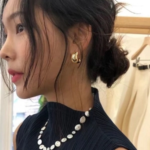 Irregular chunky C-shape golden metal earrings worn by model for an elegant minimal look