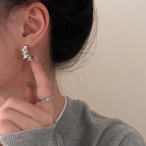 Detailed macro view of S925 silver irregular wrinkled C-shaped earrings and matching ring
