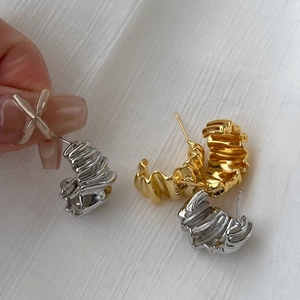 Detailed view of textured metal hoop earrings in gold and silver with fold ripples