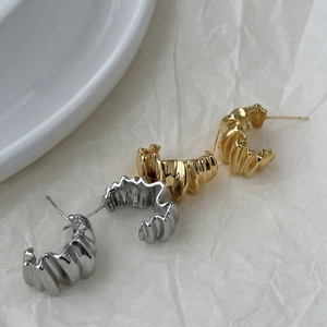 Detailed view of C-shaped earrings with unique crinkle texture in gold and silver finish