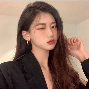 Close-up of elegant gold hoop earrings worn by a model in a professional black blazer