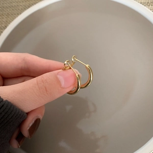 Close-up of minimalist golden hoop earrings featuring a smooth polished mirror finish