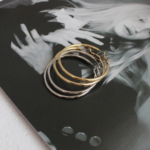 Detailed view of polished large gold and silver hoop earrings on a fashion magazine
