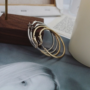 Detailed view of polished gold and silver hoop earrings on a minimalist wooden tray