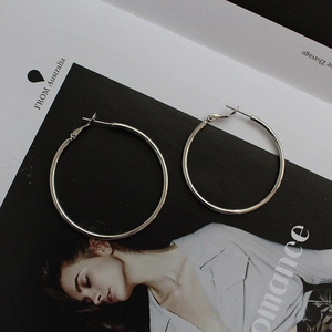Close-up of oversized silver hoop earrings with a high-polish finish on a fashion magazine