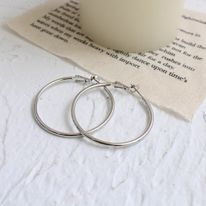 Detailed view of large silver minimalist hoop earrings with a polished mirror finish surface