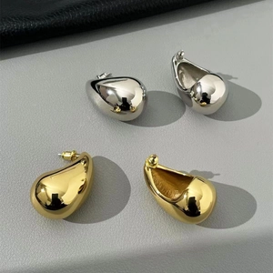Macro view of gold and silver teardrop stud earrings with a high-polished mirror finish