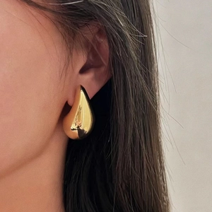 Polished 18K gold-plated teardrop open earrings on model with high-shine metallic finish