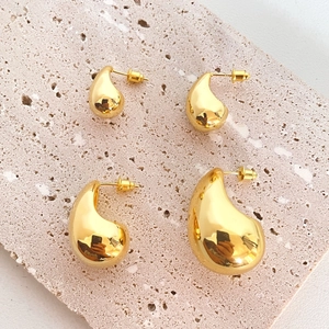 Polished 18K gold-plated teardrop stud earrings in two sizes on a stone background